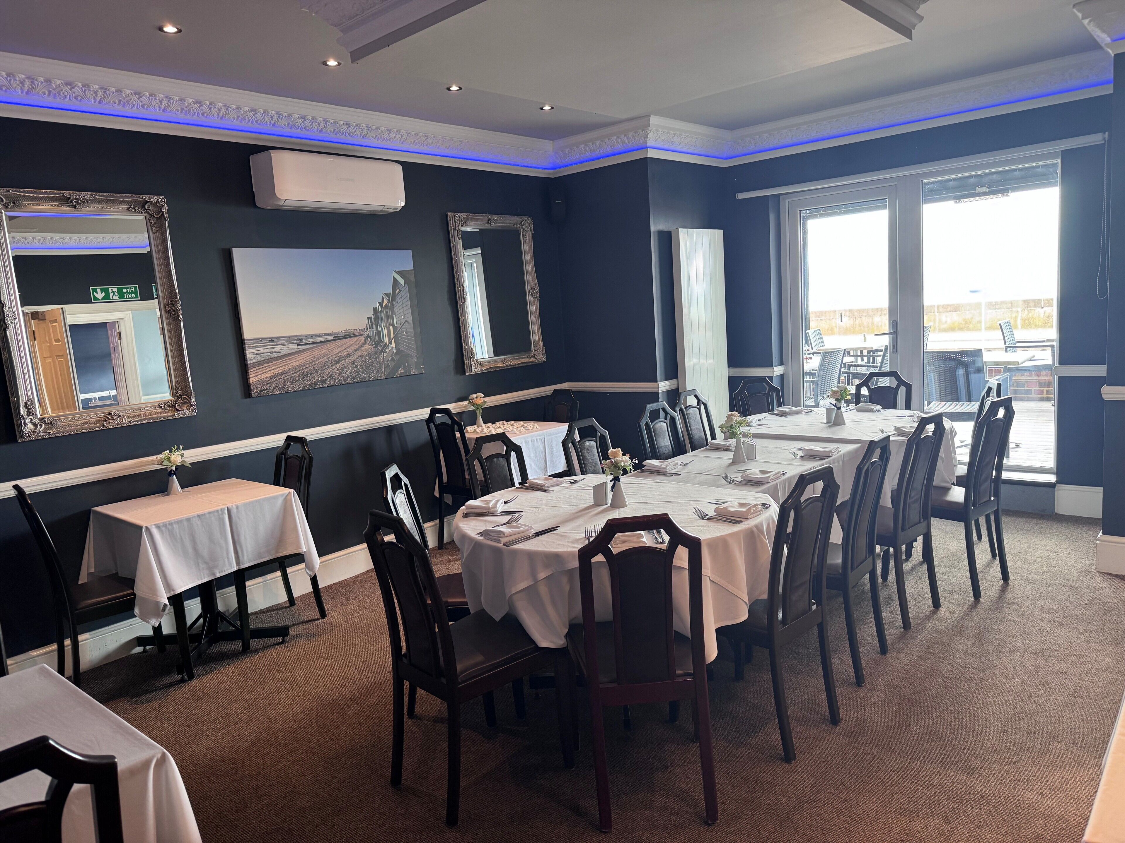 Comedor con mesas dispuestas para el servicio, sillas y vistas al exterior.