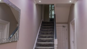 A staircase with carpeted steps and a white balustrade, leading to a room with a white door. - High Bank Hotel (Leeds)