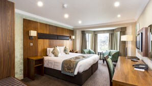 Ein Hotelzimmer mit einem großen Bett, einem Schreibtisch, einem Stuhl und einem Fernseher.