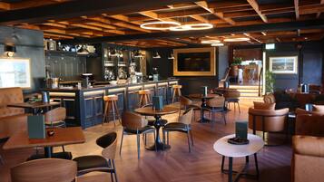 Zona de bar moderna con vigas de madera en el techo, iluminación colgante y una barra con taburetes.