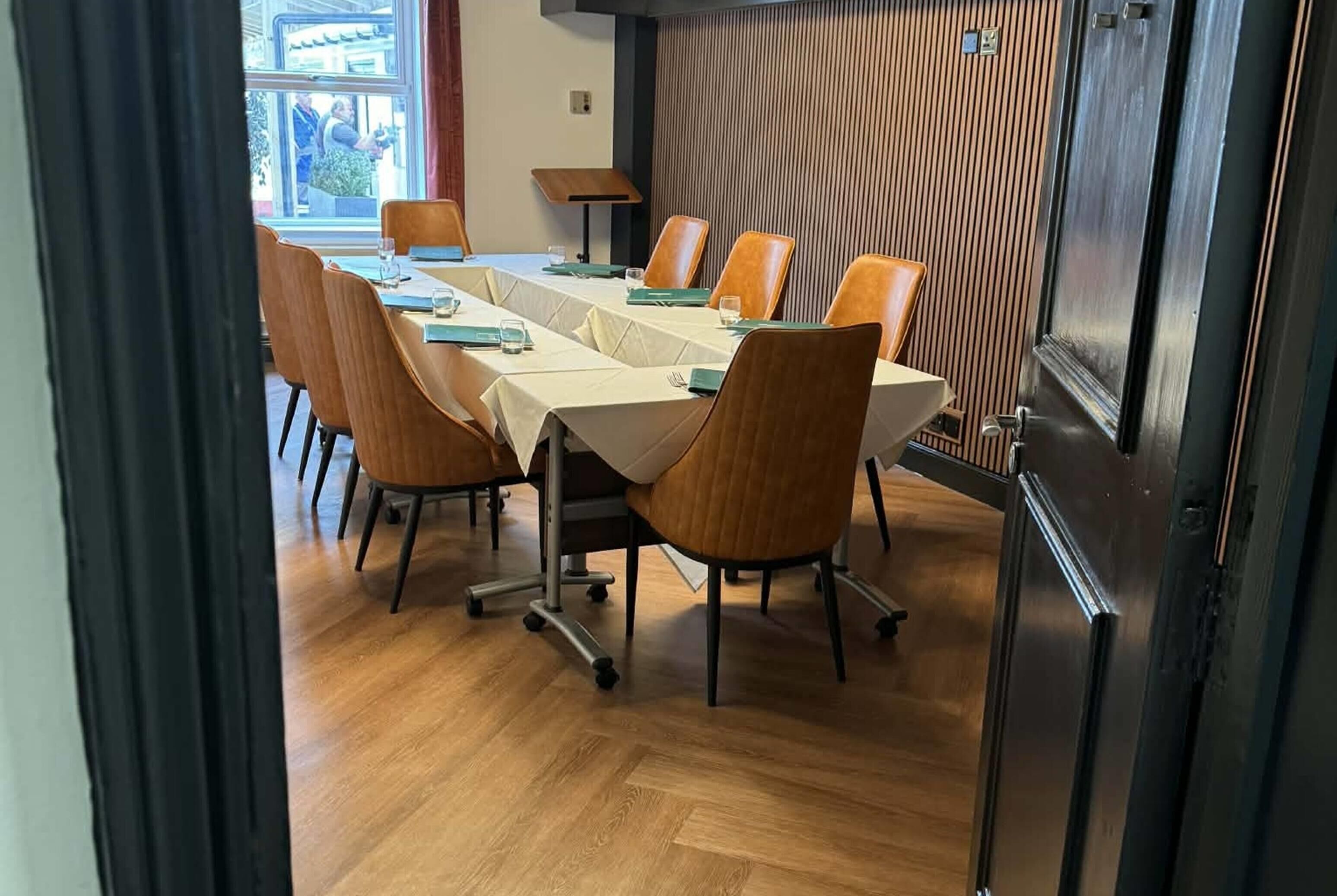 A conference room with a long table, chairs, and a wooden panel wall.