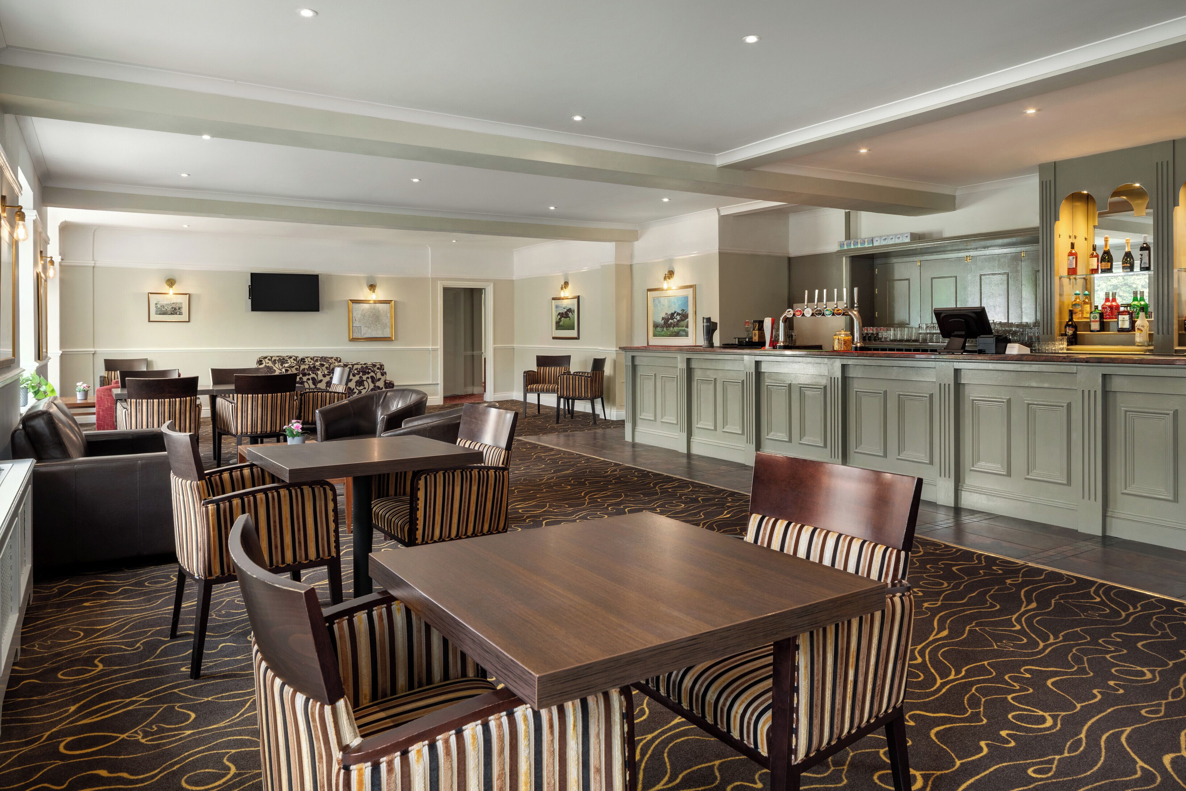 A spacious hotel lobby with a bar area, seating arrangements, and a patterned carpet.