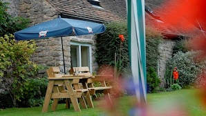 A stone building with a wooden table and chairs under a blue umbrella. - The Gaskell Arms Hotel (Much Wenlock)