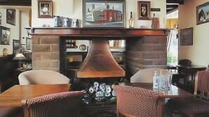 A cozy pub with a brick fireplace, wicker chairs, and framed pictures on the walls. - The Gaskell Arms Hotel (Much Wenlock)