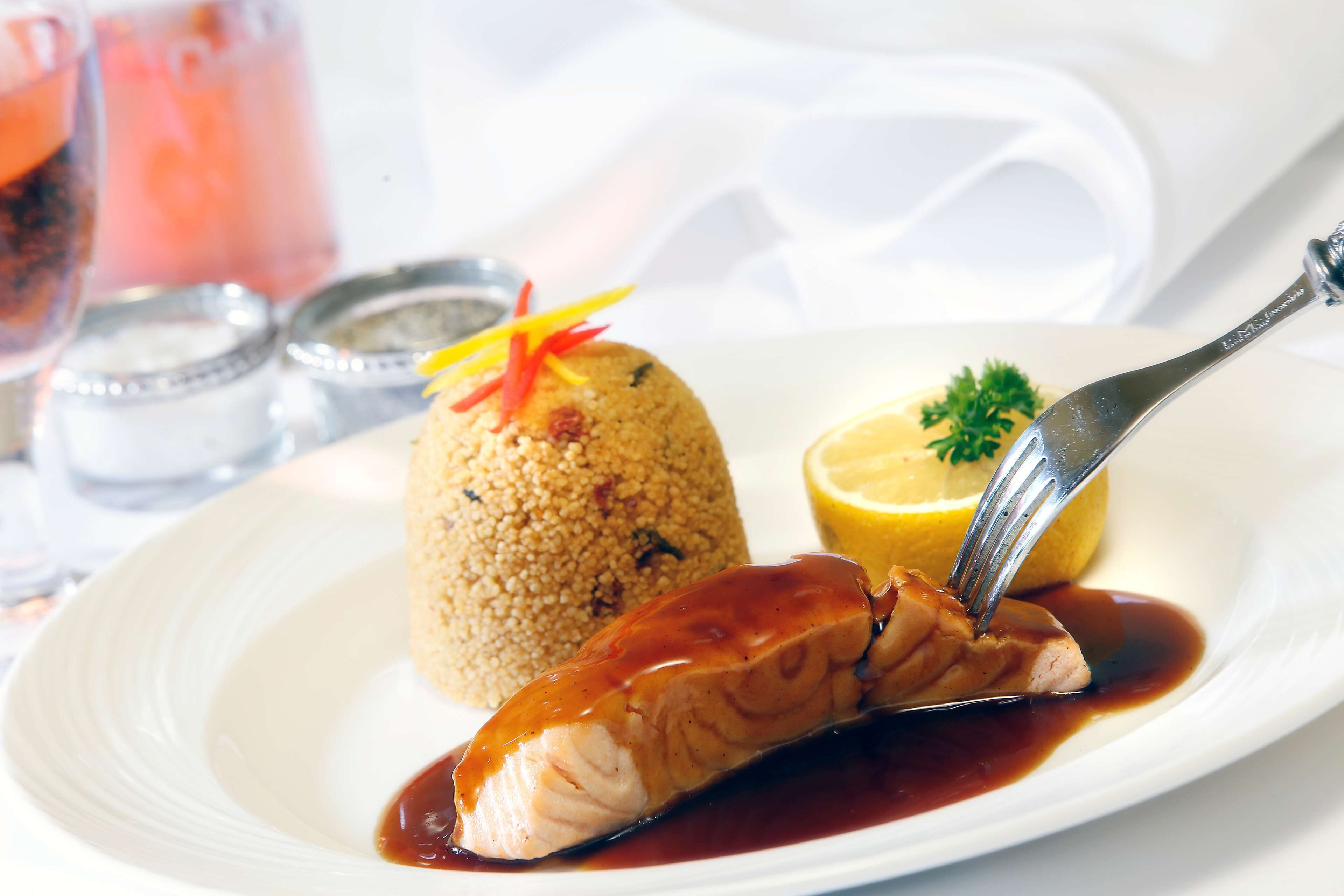 A plate with salmon, a mound of couscous, and a lemon wedge.