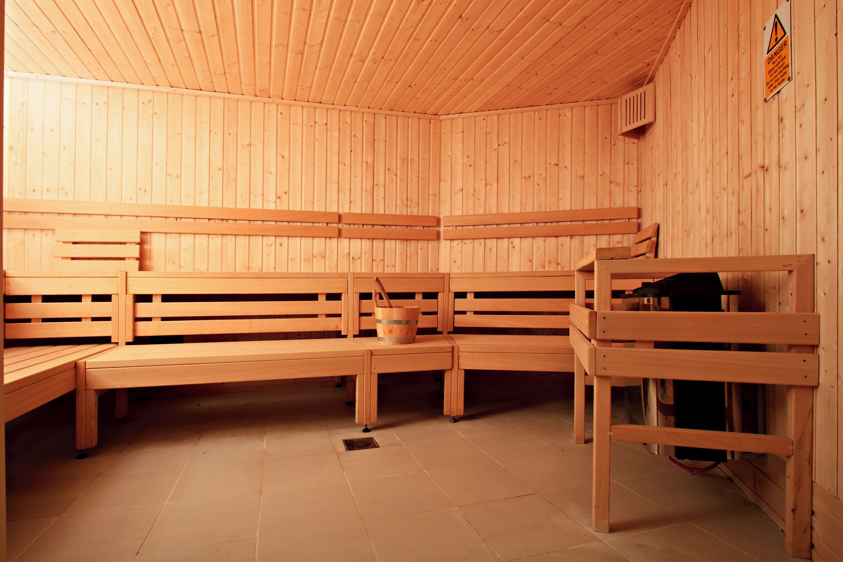 Een sauna met houten banken en een emmer.