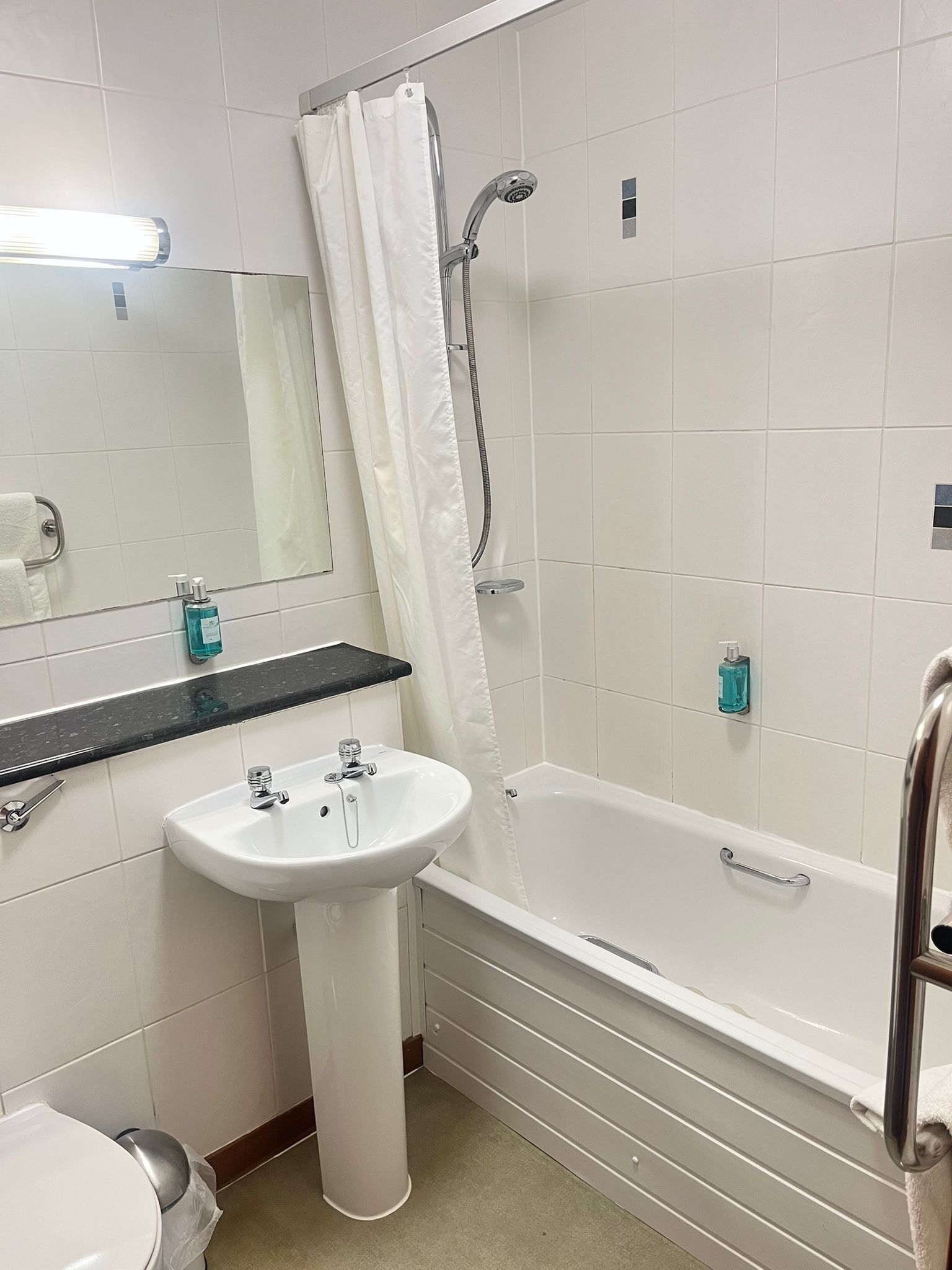 A bathroom with a white sink, a mirror, a shower with a curtain, and a bathtub.