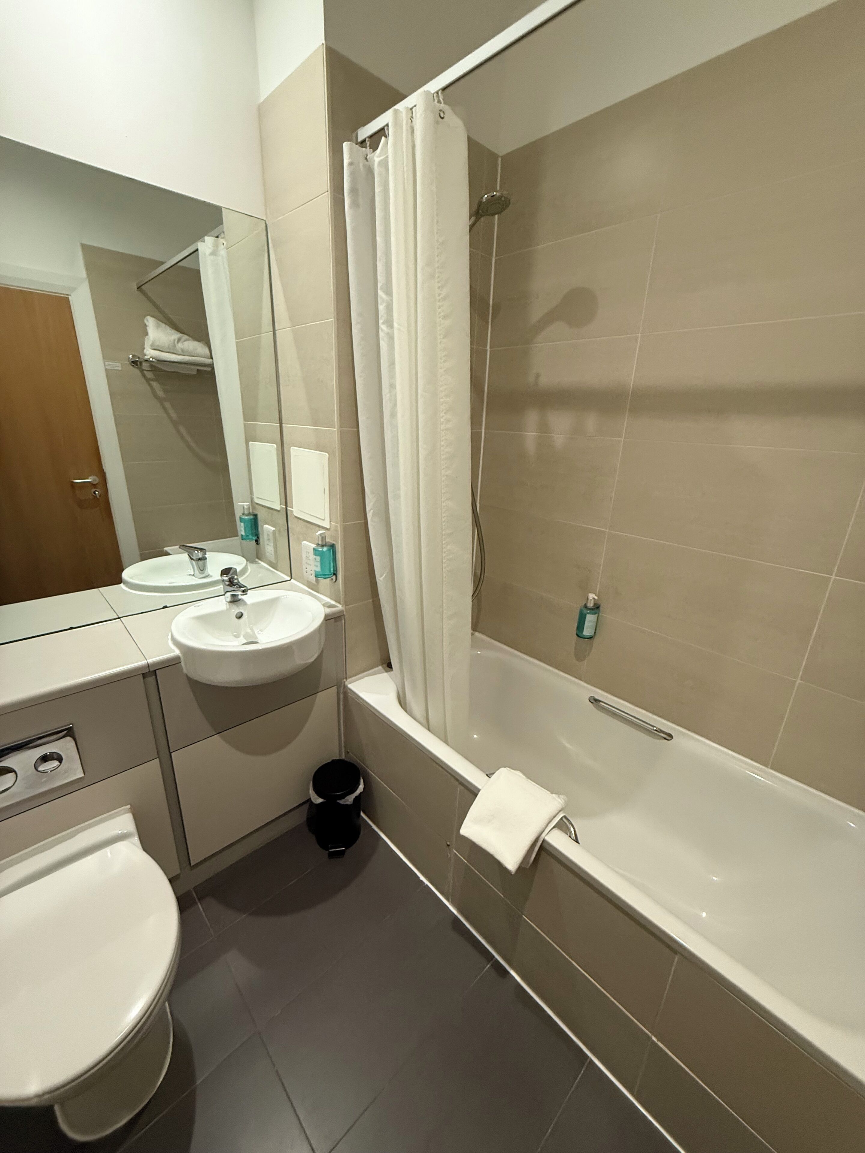 Un baño moderno con lavamanos, espejo y bañera blancos.