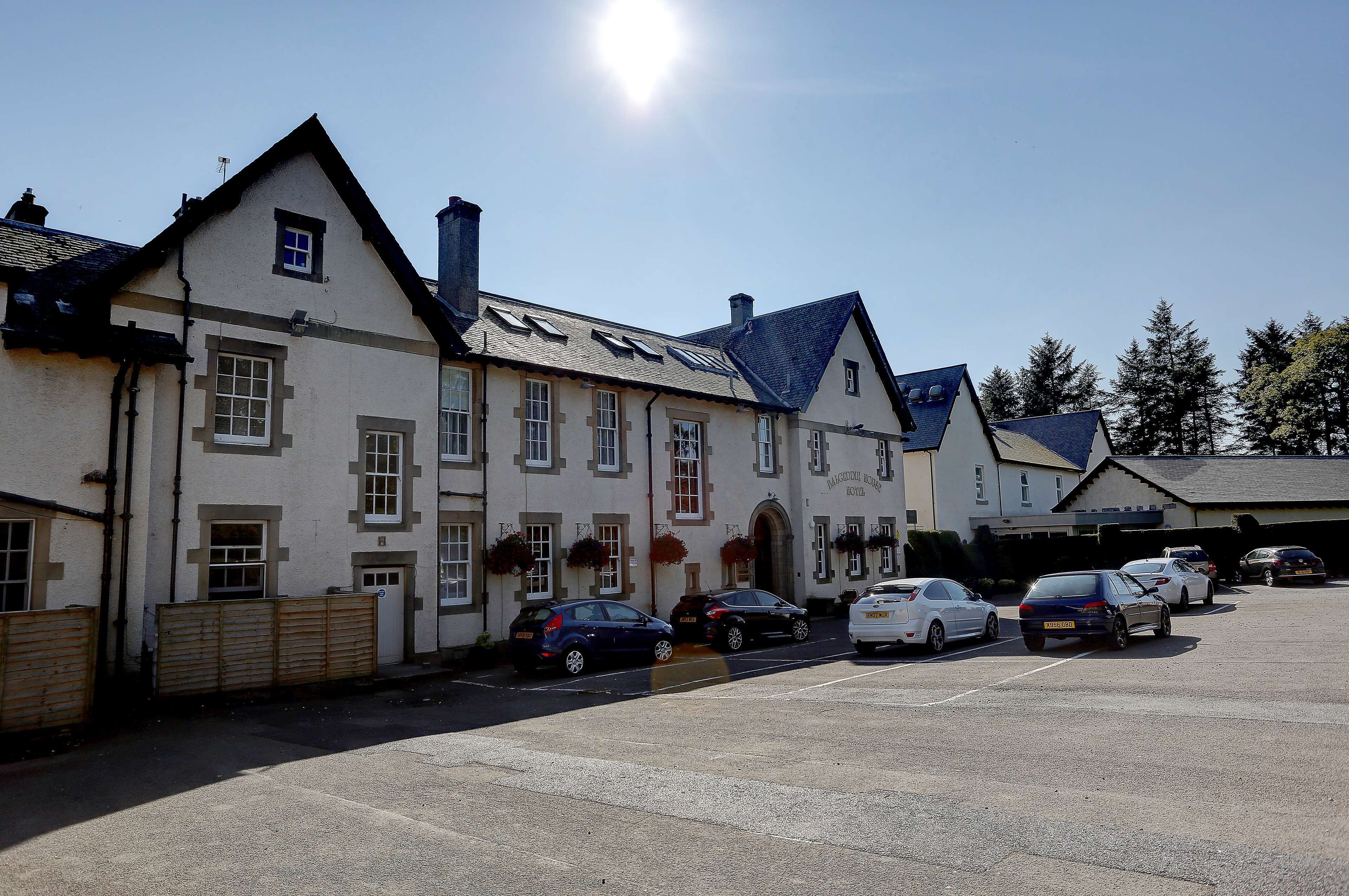 A building with multiple windows and a parking lot with several cars.