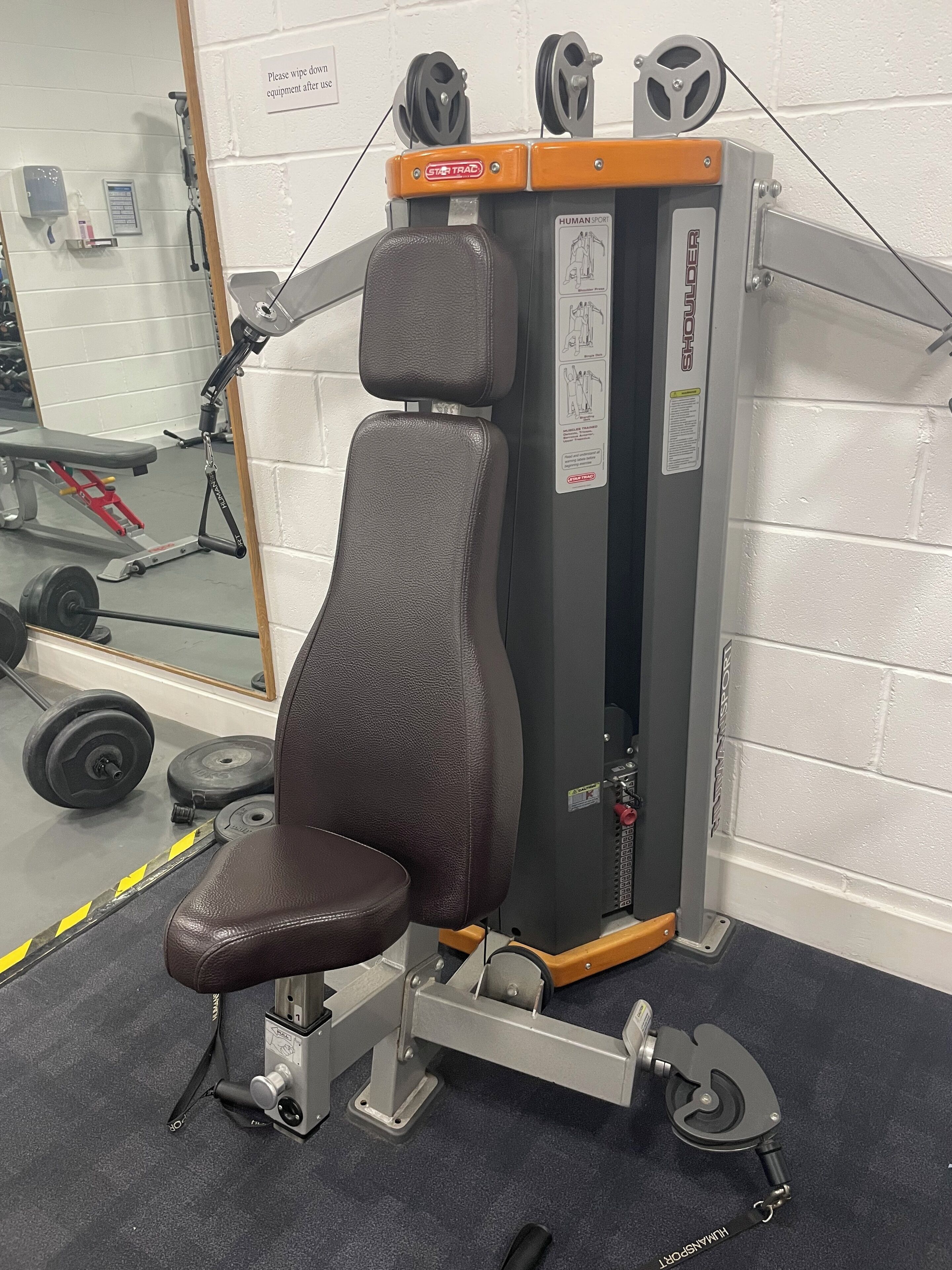 Ein Fitnessraum mit Gewichtsbank, Kabelzugmaschine und Spiegel.