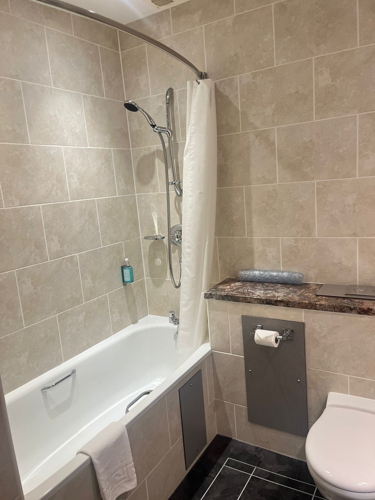A bathroom with a bathtub, toilet, and shower area.