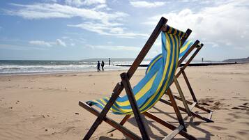 Una silla de playa con un cojín a rayas sobre arena.