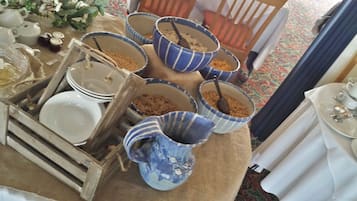 A room with a dining area featuring a table set with plates, bowls, and a teapot.