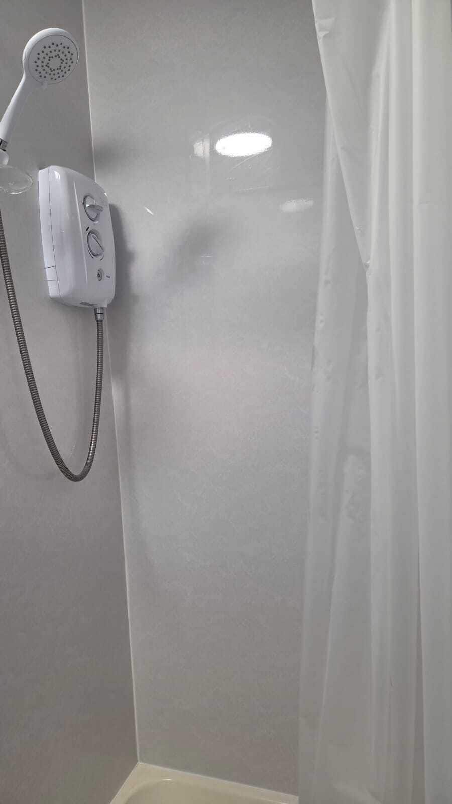 Zona de ducha con ducha de mano y panel de control.