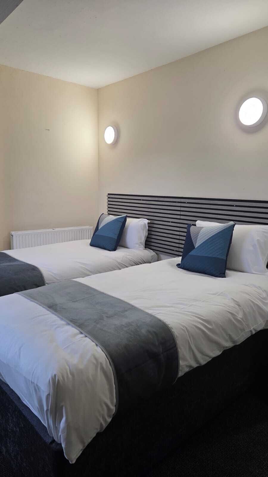 Ein Hotelzimmer mit zwei Betten, einem Heizkörper und zwei Wandleuchten.