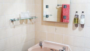 A bathroom with a sink, mirror, and two bottles of hand soap.