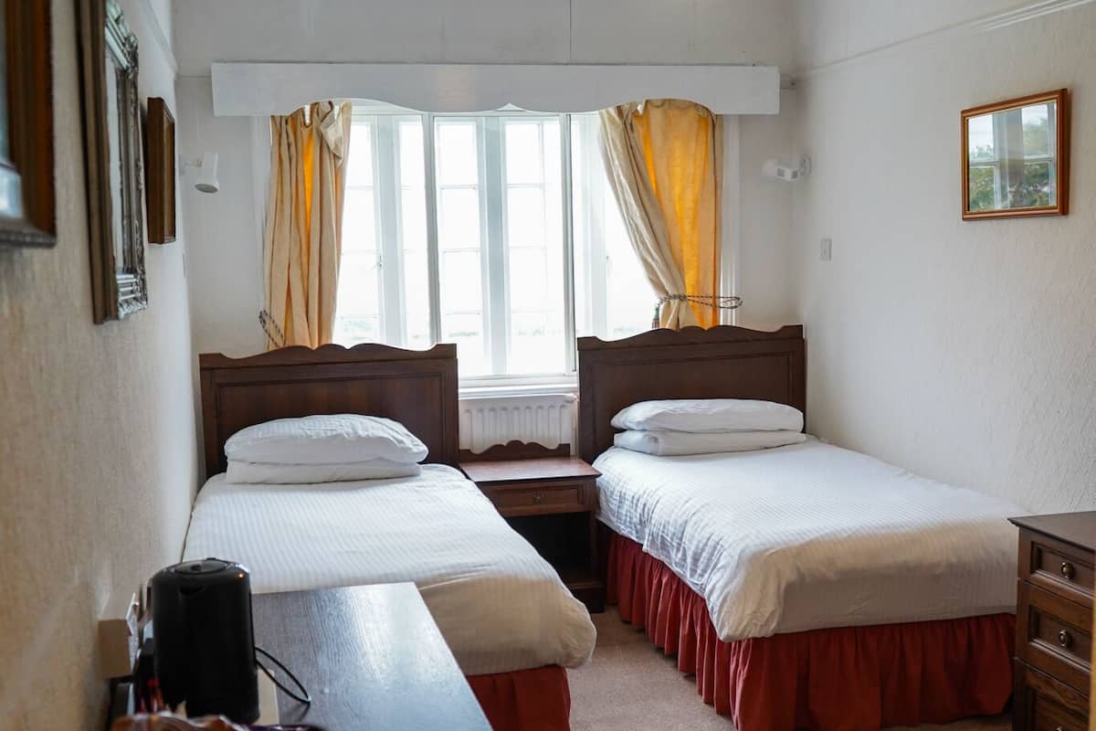 A room with two beds, a desk, and a chair.