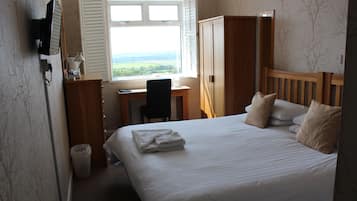 A hotel room with a bed, a desk, a chair, and a wardrobe.