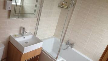 A bathroom with a sink, mirror, and shower.