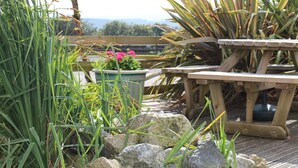 A wooden deck with a table and chairs, surrounded by rocks and plants.