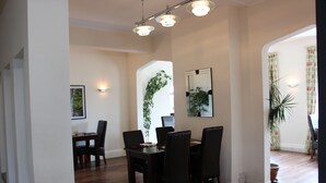 A dining area with a dark wooden table and chairs, a potted plant, and a mirror on the wall.