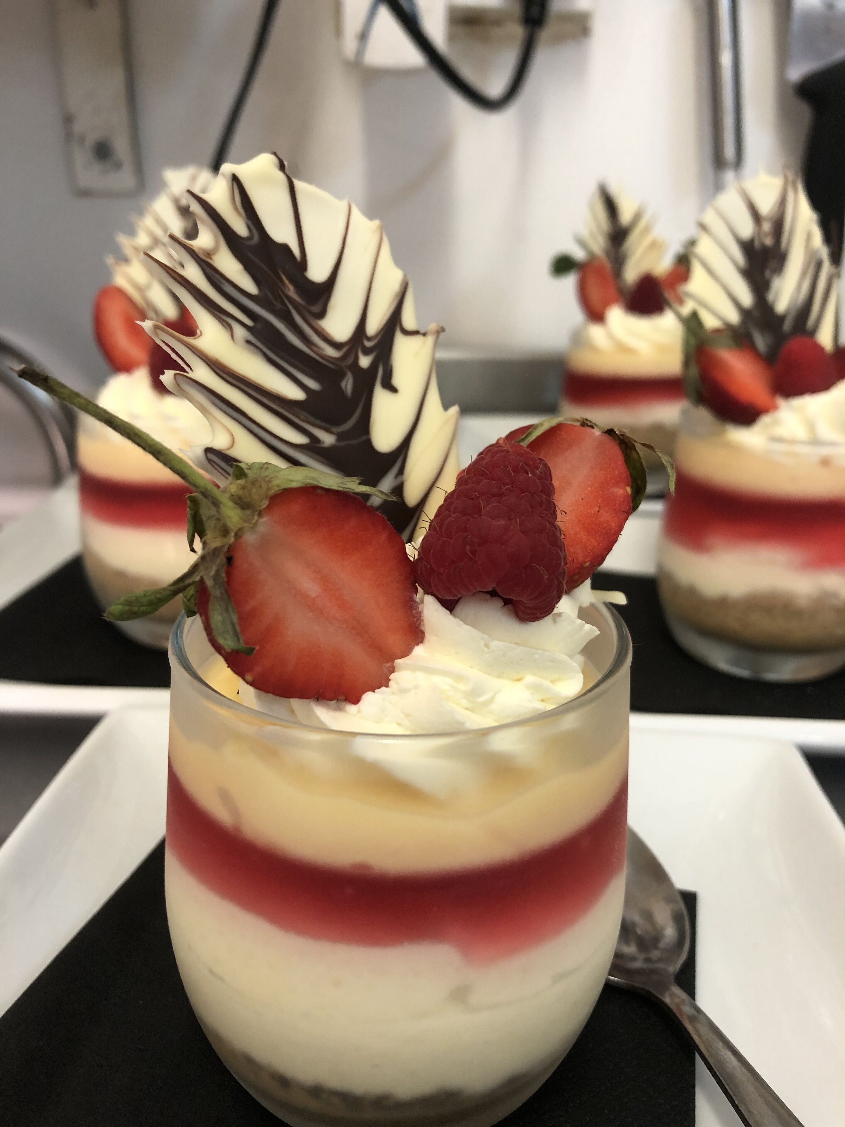 A dessert with layers of cream and fruit, garnished with strawberries and chocolate.