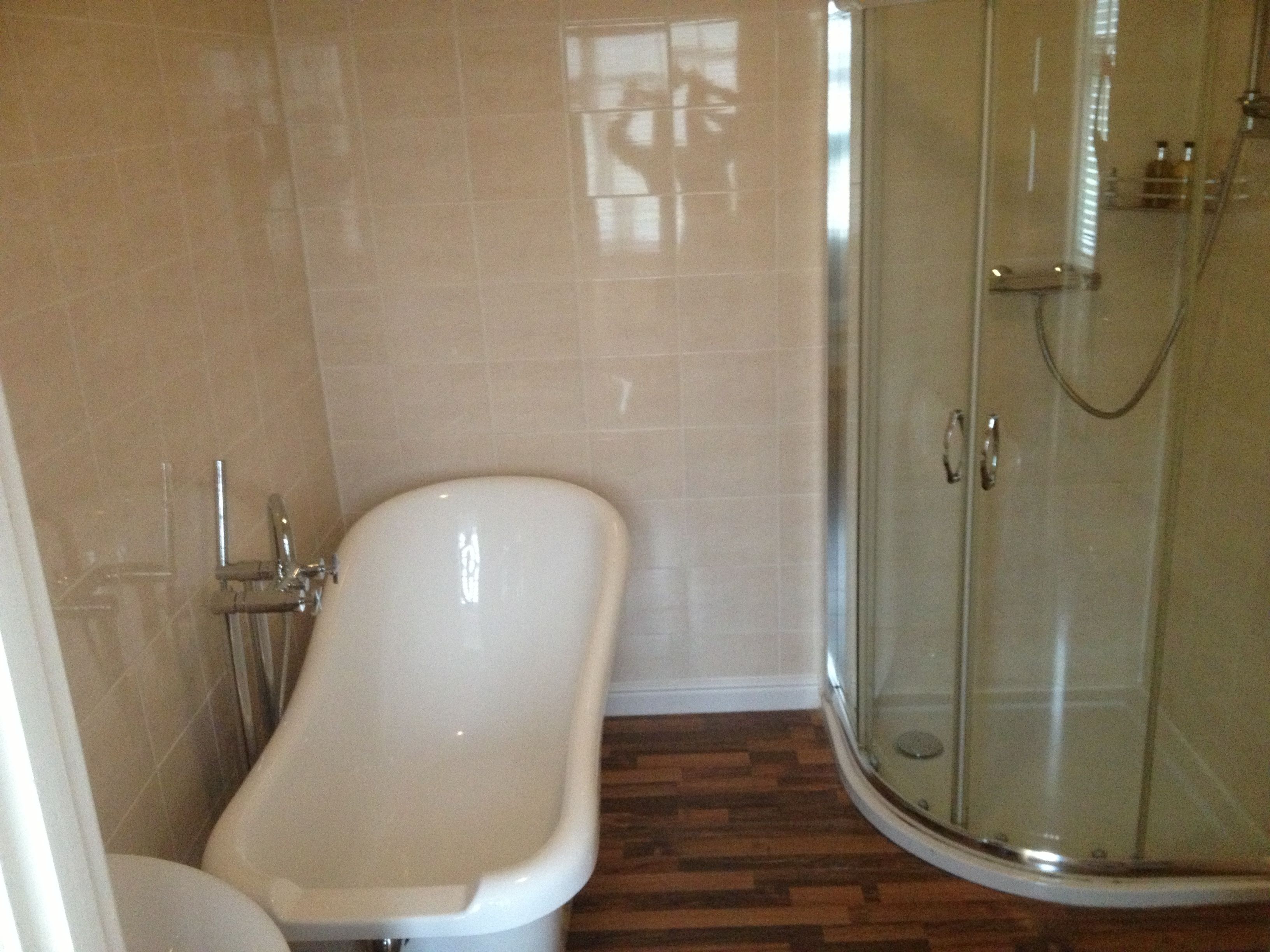 A bathroom with a bathtub, toilet, and glass shower enclosure.