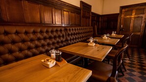 Restaurante com bancos e mesas de madeira, destacando um padrão quadriculado no chão.