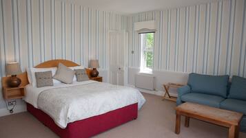 A bedroom with a bed, bedside tables, a blue sofa, and a wooden bench.