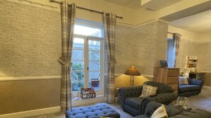 A living room with a large window, a lamp, a sofa, and a cabinet. - Lynton House (Llandudno)