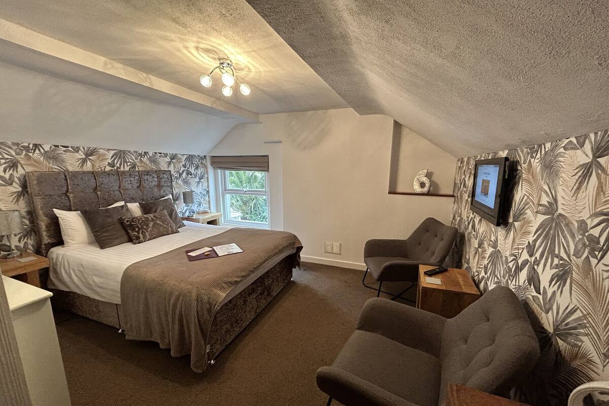 A bedroom with a bed, a chair, a TV, and a window.
