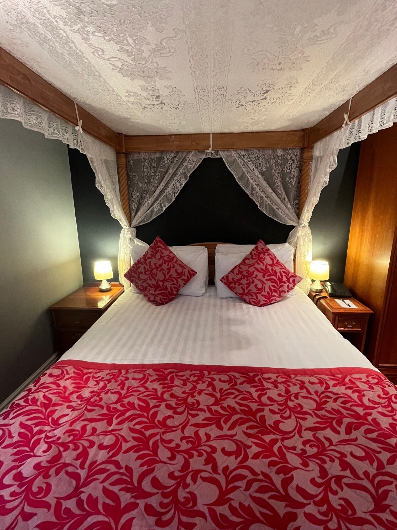 A bed with a canopy, two bedside tables with lamps, and a patterned bedspread.