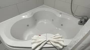Une salle de bain moderne avec une baignoire sur pieds, une douchette et une serviette suspendue au bord de la baignoire.