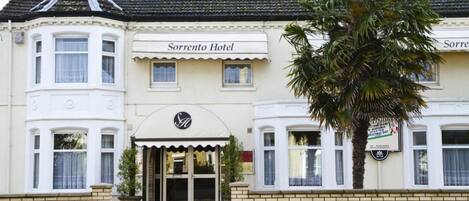 Un edificio de dos pisos con un letrero que dice "Sorrento Hotel" y una palmera frente a él.