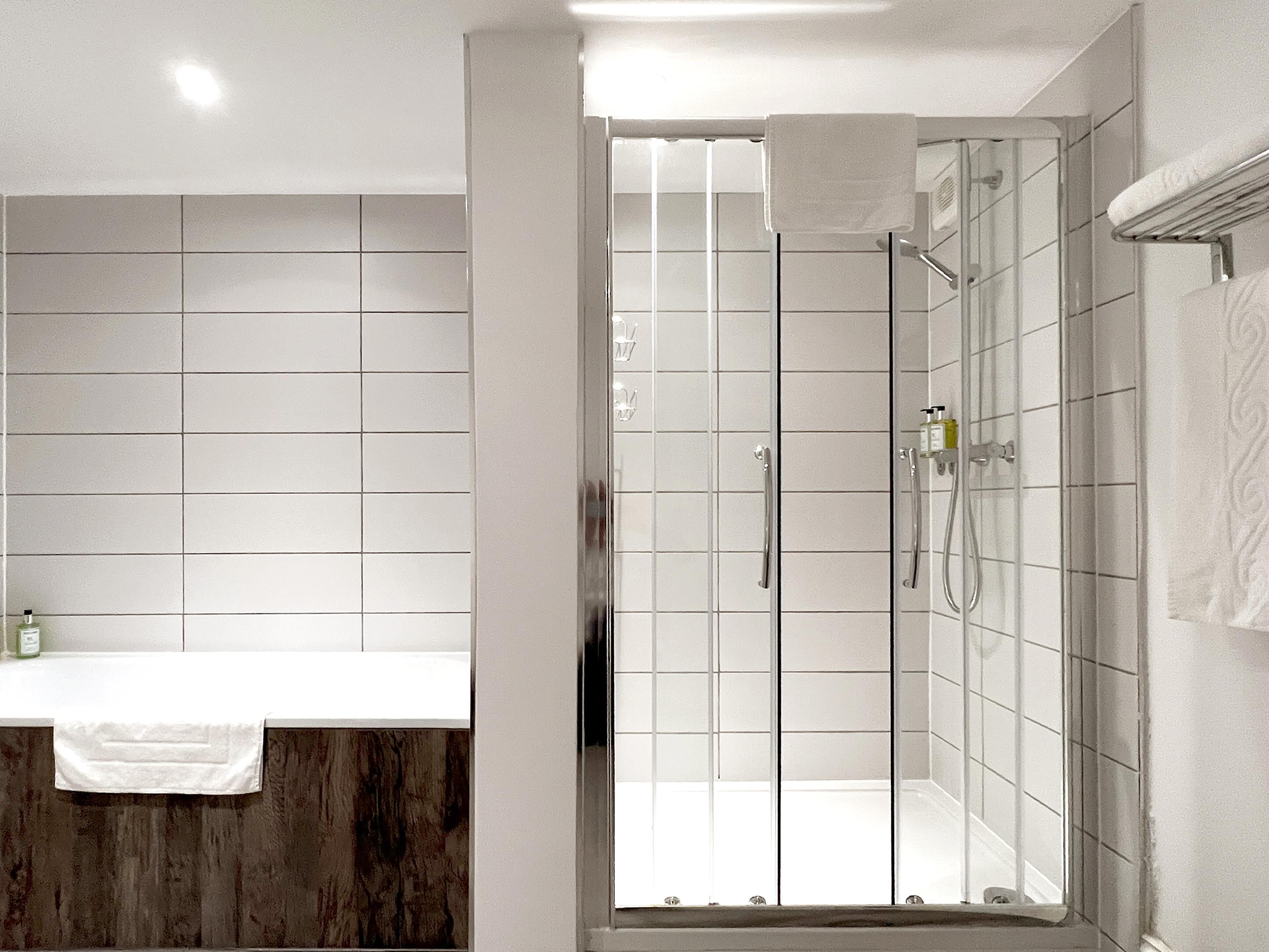 A modern bathroom with a glass-enclosed shower, a wooden vanity, and a white sink.