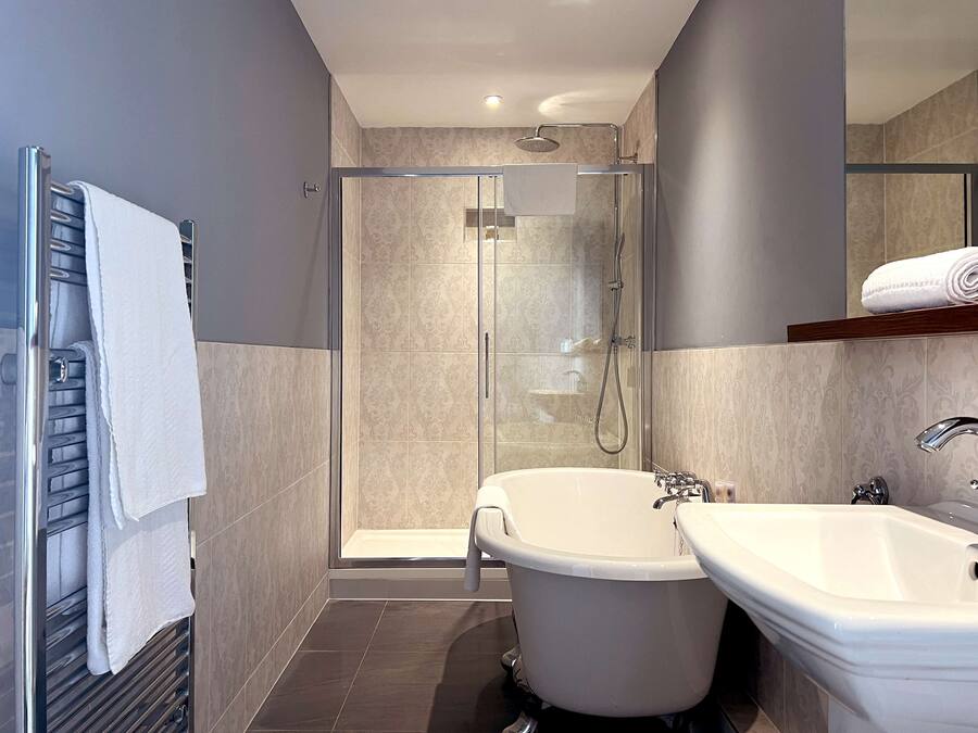 Un baño moderno con ducha de vidrio, una bañera independiente y un lavamanos.
