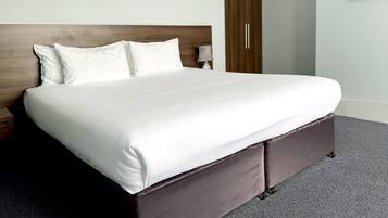 A neatly made bed with white linens, a wooden headboard, and a dark brown footboard.