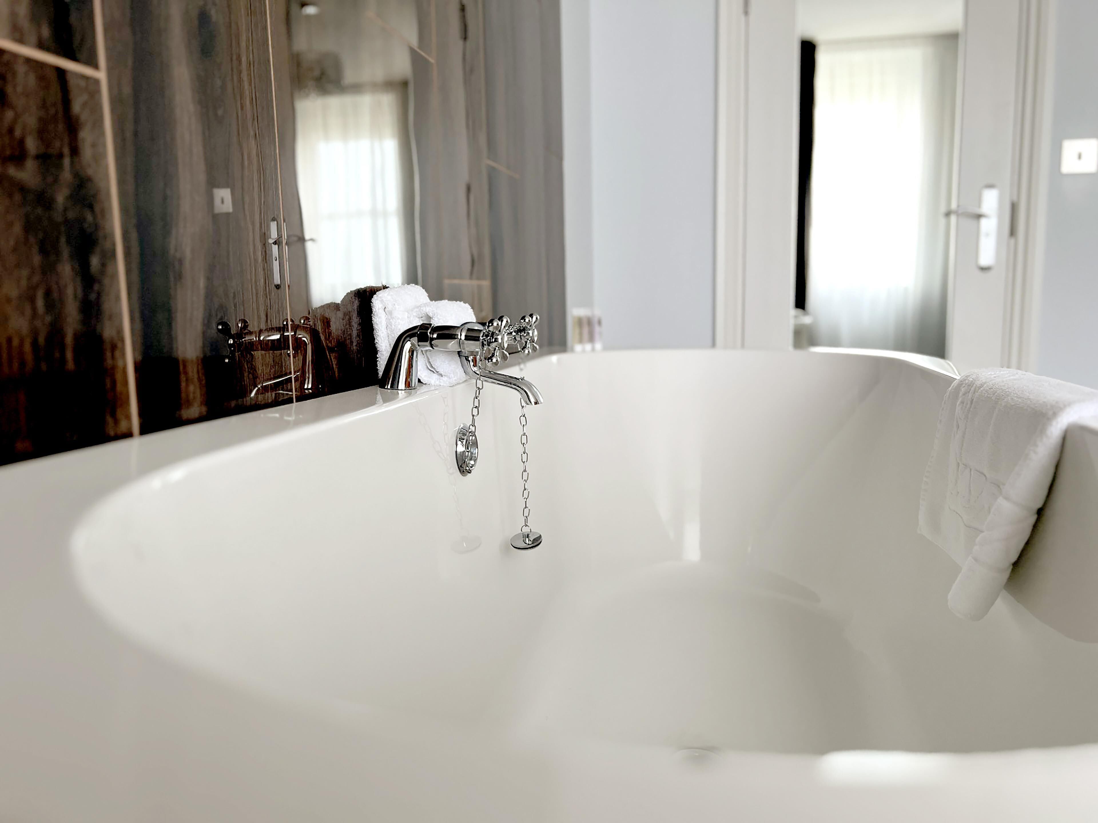 Une salle de bain moderne avec une baignoire sur pieds, un grand miroir et un mur en bois.