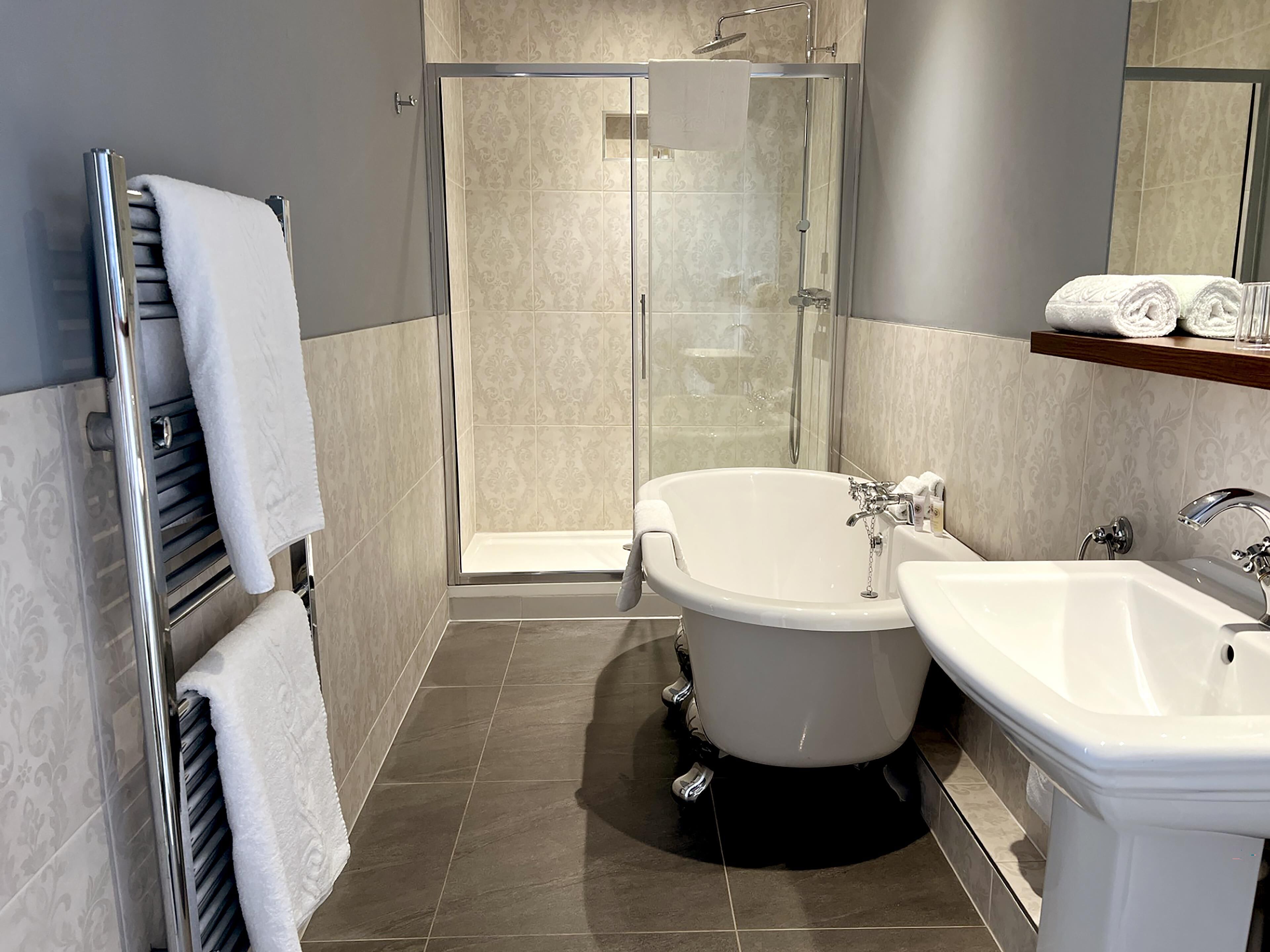 Een moderne badkamer met een douche met glazen wand, een vrijstaand bad en een wastafel.