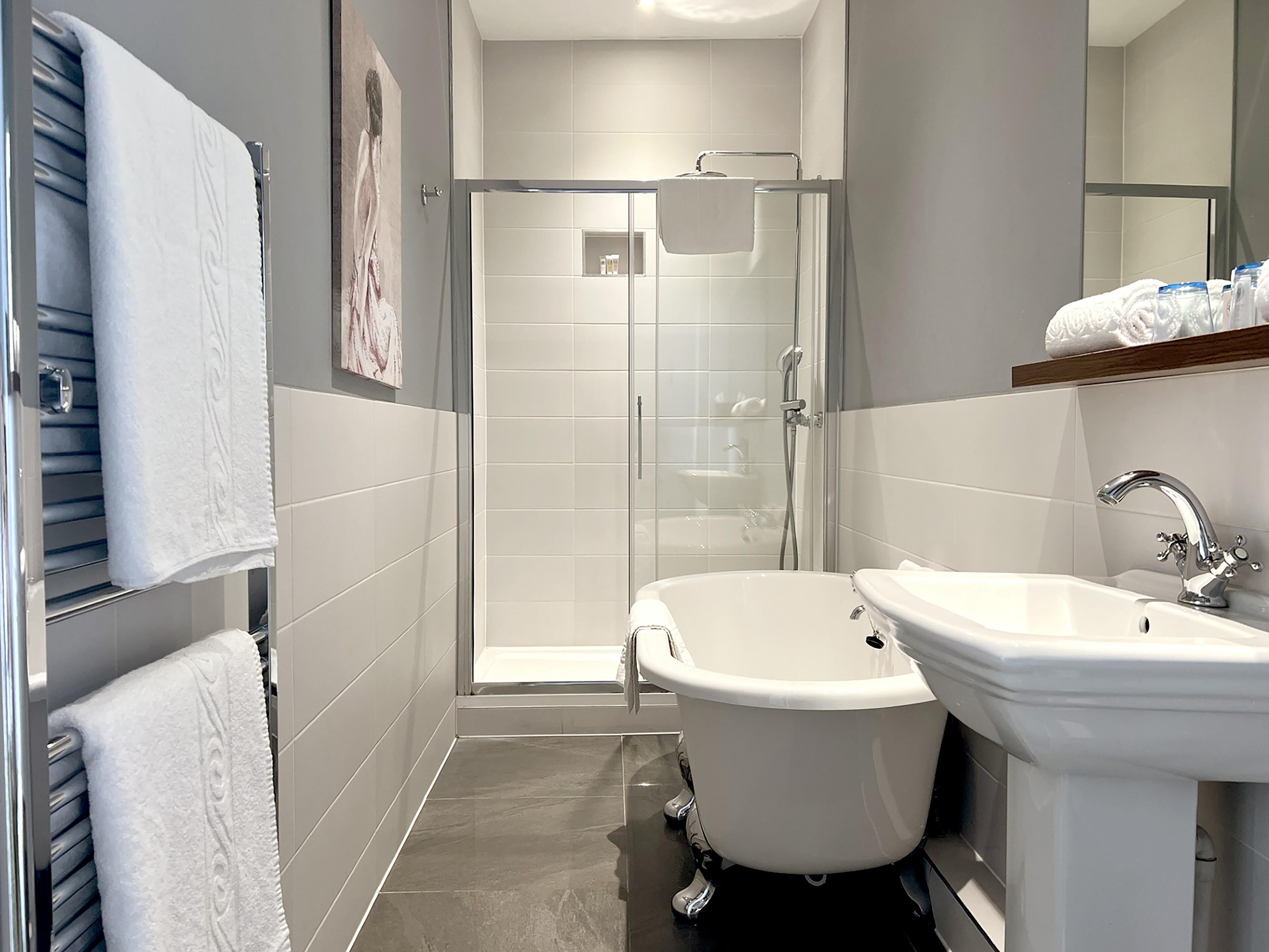 A modern bathroom with a glass-enclosed shower, a freestanding bathtub, and a pedestal sink.