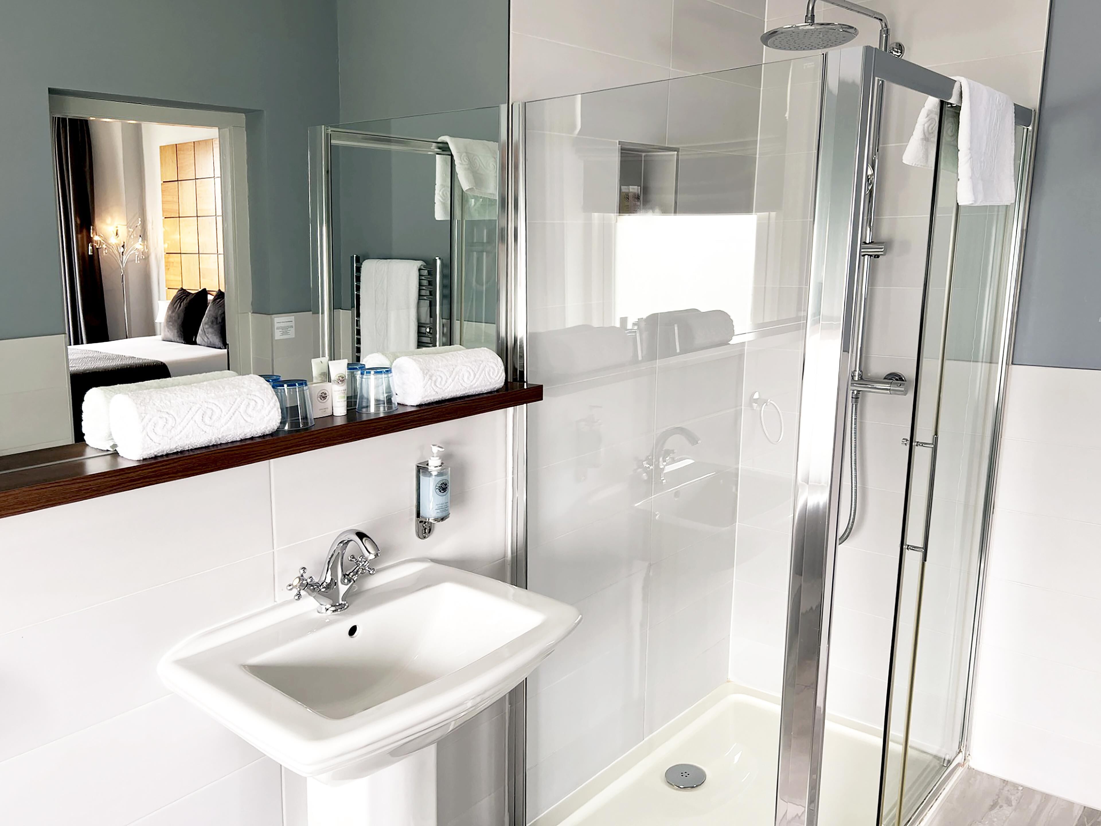 A modern bathroom with a glass-enclosed shower, a white sink, and a mirror above the sink.
