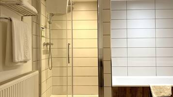 A modern bathroom with a glass-enclosed shower, a white tiled wall, and a wooden panel.