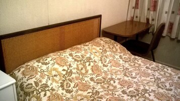 A room with a bed, a small table, and a chair.