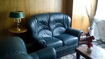 Een kamer met een leren bank, een klein rond tafeltje en een lamp.