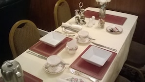 A dining table set with white and pink tableware, including plates, bowls, and cups, arranged on a white tablecloth with red placemats. - The Albert Hotel Near Winter Gardens (Blackpool)
