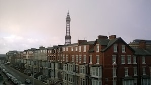 A row of terraced houses with a prominent tower in the background. - The Albert Hotel Near Winter Gardens (Blackpool)