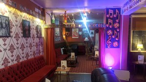 A cozy bar area with a red sofa, a black leather chair, and a wooden table with a menu. - The Albert Hotel Near Winter Gardens (Blackpool)