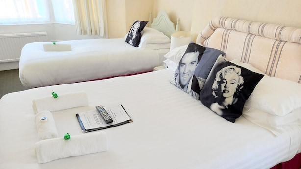 Two neatly made beds with white linens, pillows with a black and white design, and a remote control on the bed. - The Albert Hotel Near Winter Gardens (Blackpool)