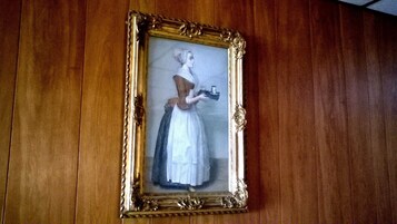 A framed painting of a woman in a white dress on a wooden wall.
