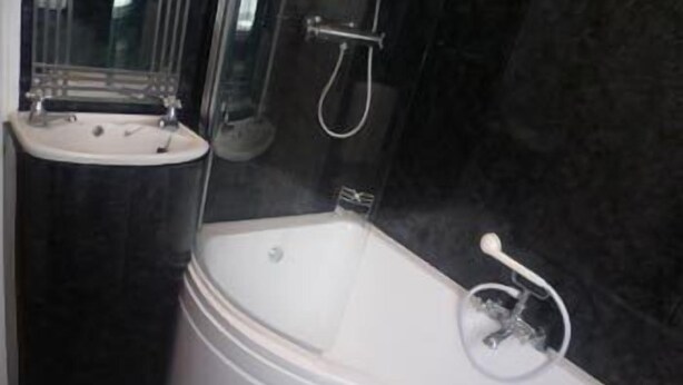 A modern bathroom with a bathtub, a sink, and a glass shower enclosure. - Ansteys Lea Guest House (Torquay)